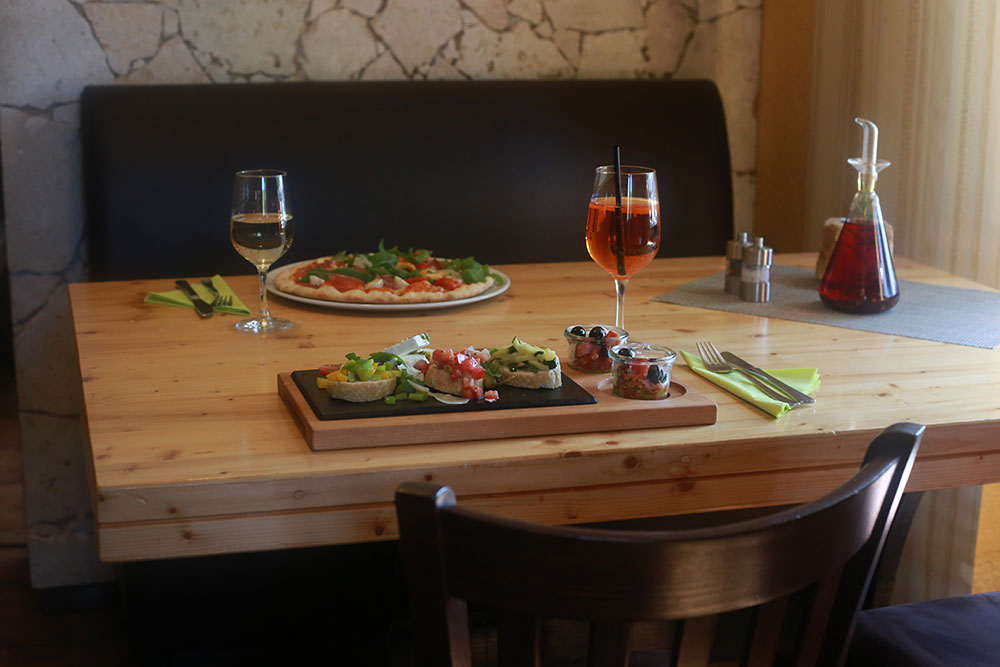 Pizza und Aperitif auf gemütlich gedecktem Tisch